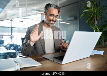 Glücklicher Geschäftsmann mittleren Alters mit virtuellem Meeting, der im Büro arbeitet. Stockfoto