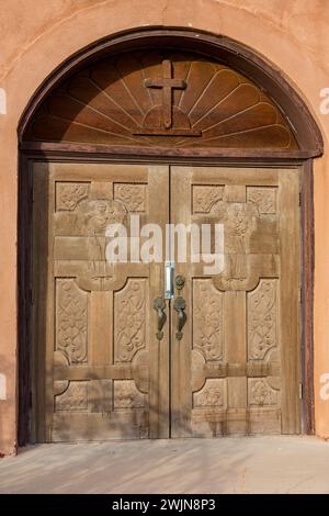 Geschnitzte Holztüren der alten katholischen Pfarrkirche im Missionsstil in San Antonio, einer kleinen Stadt im ländlichen New Mexico. Stockfoto