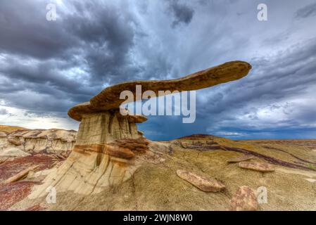 Der King of Wings, ein sehr zerbrechlicher Sandstein-Hoodoo in den Badlands des San Juan Basin in New Mexico, mit Sturmwolken dahinter. Stockfoto