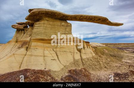 Der King of Wings, ein sehr zerbrechlicher Sandstein-Hoodoo in den Badlands des San Juan Basin in New Mexico, mit Sturmwolken dahinter. Stockfoto