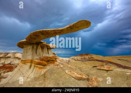 Der King of Wings, ein sehr zerbrechlicher Sandstein-Hoodoo in den Badlands des San Juan Basin in New Mexico, mit Sturmwolken dahinter. Stockfoto