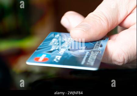 Männliche Hand, die eine Zahlungskarte hält. Blaue Karte. Stockfoto