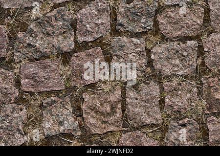 Fragment einer asphaltierten Steinstraße. Die Hintergrundstruktur des braunen Steinpflasters. Beispiel. Stockfoto