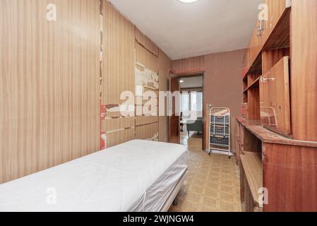 Ein Zimmer mit Möbeln und Wänden in schlechtem Zustand und einer Matratze ohne Bettwäsche Stockfoto