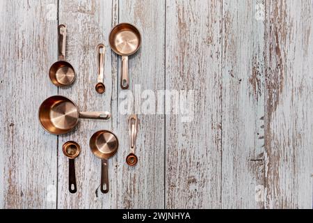 Stillleben mit einigen Messbecher aus Kupfer unterschiedlicher Größe auf einer Holzoberfläche Stockfoto