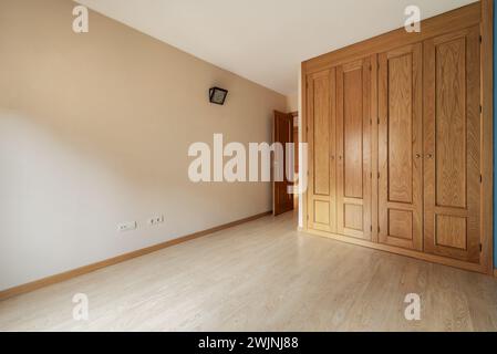 Ein leerer Raum mit eingebautem Kleiderschrank, der eine Wand mit raumhohen Holztüren bedeckt Stockfoto