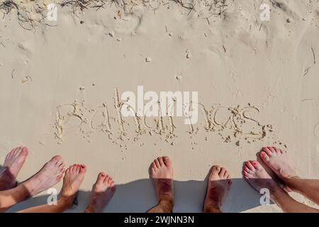 Usa. Februar 2024. Friends' Caribbean Escape: Urlauber schreiben „Bahamas“ in den Sand, die Zehen sind eingetaucht und fangen sonnenverwöhnte Momente an ihrem idyllischen Strandurlaub ein (Credit Image: © Walter G Arce SR Grindstone Medi/ASP) NUR REDAKTIONELLE VERWENDUNG! Nicht für kommerzielle ZWECKE! Stockfoto