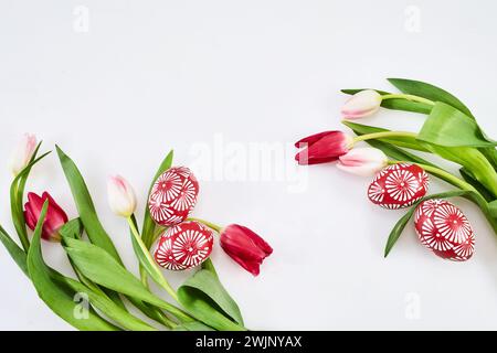 Wunderschöne Tulpen mit bunten Eiern auf hellem Hintergrund. Frühjahrs- und Osterferienkonzept Stockfoto