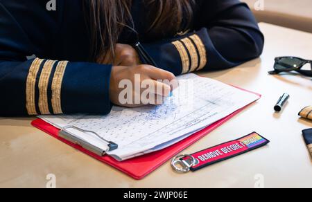 Nicht erkennbare Pilotin, die Flugdokumentation mit einem Schlüsselanhänger „Entfernen vor dem Flug“ vorbereitet. Hochwertige Fotos Stockfoto