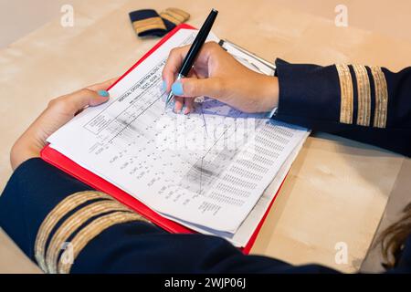 Nicht erkennbare Pilotin, die Flugdokumentation mit einem Schlüsselanhänger „Entfernen vor dem Flug“ vorbereitet. Hochwertige Fotos Stockfoto