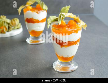 Mehrschichtiges Dessert mit Proteinjoghurt und Physalis-Früchten auf grauem Tisch Stockfoto