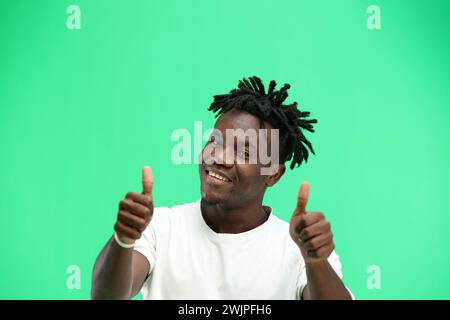 Ein Mann aus der Nähe, auf grünem Hintergrund, zeigt seine Daumen nach oben. Stockfoto