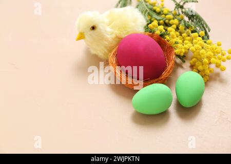 Komposition mit Ostereiern, Küken und Mimosa auf beigem Hintergrund Stockfoto