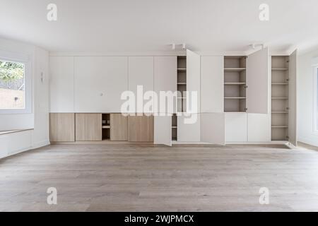 Wohnzimmer eines kürzlich renovierten leeren Hauses mit weiß bemalten Wänden und einem Bücherregal mit offenen weißen Holztüren mit vielen Regalen im Inneren Stockfoto