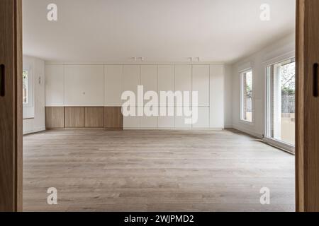 Wohnzimmer eines kürzlich renovierten leeren Hauses mit weiß lackierten Wänden und einem Bücherregal mit weißen Holztüren von den Eichenholztüren aus gesehen Stockfoto