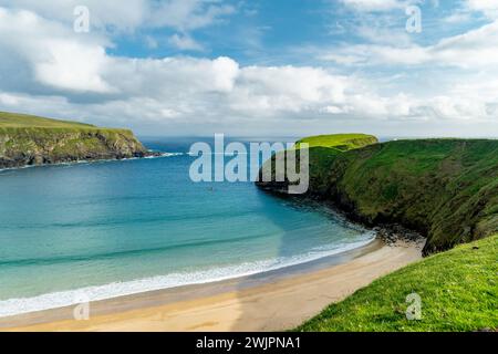 Schafe weiden in der Nähe von Silver Strand, einem Sandstrand in einer geschützten, hufeisenförmigen Bucht, in Malin Beg, in der Nähe von Glencolmcille, im Südwesten des Countys Stockfoto