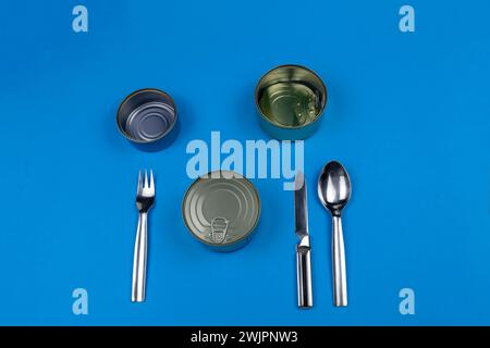 Besteck Messer Gabellöffel Dosen leer geschlossen auf blauem Besteck. Nichts zum Abendessen. Was willst du auf den Teller legen? Stockfoto