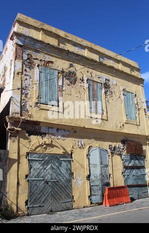 Verlassenes Gebäude aus gelbem Stein mit blauen Holzläden in Charlotte Amalie, St. Thomas, US-Jungferninseln Stockfoto