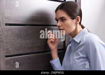 Frau im Hemd klopft drinnen an die Tür Stockfoto