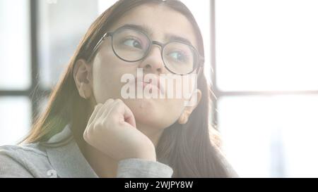 Eine junge Frau mit Brille im Büro denkt nach Stockfoto