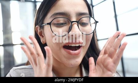 Das Gesicht einer jungen Frau in Nahaufnahme mit einer Brille im Büro, sie ist überrascht Stockfoto