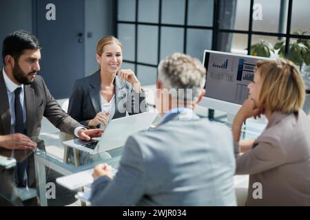 Eine vielfältige Gruppe lächelnder Geschäftsleute, die sich miteinander unterhalten Stockfoto
