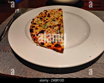 Bild von halbgeschnittenem Käse Naan, serviert in einem weißen Gericht Stockfoto