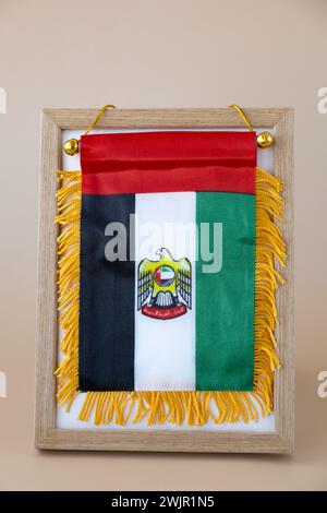 Nationales Symbol der VAE. Kleine Flagge der Vereinigten Arabischen Emirate mit Wanderfalke auf neutralem beigem Hintergrund. Kopieren Sie den Platz für Ihren Text. Das Konzept der Unabhängigkeit des Nationaltages Stockfoto