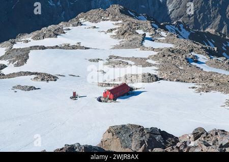 Gemütliche rote Hütte inmitten der schneebedeckten Wildnis: Mueller Hut eingebettet in Neuseelands spektakuläres Berggebiet Stockfoto