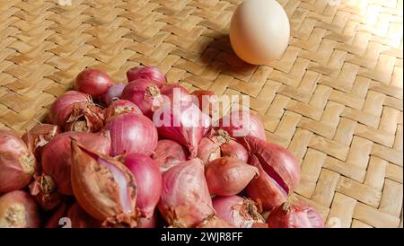 Foto von Gewürzen in Form von Schalotten, Knoblauch, Chilis und Eiern, die in einem gewebten Bambus angeordnet sind Stockfoto