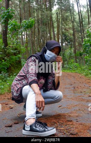 Wonosobo, Indonesien 1-3-2021 eine Frau, die ein schwarzes Kopftuch trägt und eine Maske mit verschiedenen Stilen trägt, ein Fotokonzept, um die Ausbreitung der Corona zu verhindern Stockfoto