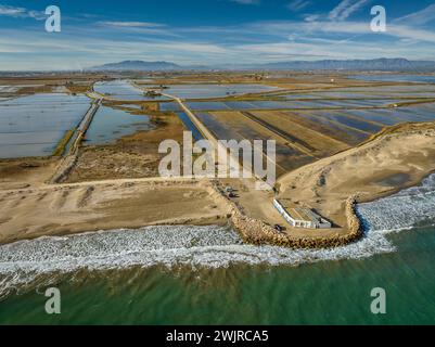 Blick aus der Vogelperspektive auf den Strand von Marquesa und das Restaurant Vascos, mit einem Felsdamm gegen die Regression des Ebro-Deltas (Tarragona, Katalonien, Spanien) Stockfoto