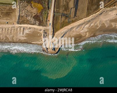 Blick aus der Vogelperspektive auf den Strand von Marquesa und das Restaurant Vascos, mit einem Felsdamm gegen die Regression des Ebro-Deltas (Tarragona, Katalonien, Spanien) Stockfoto