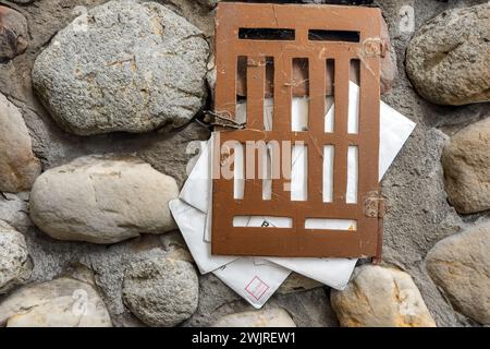 Briefkasten voller Briefe an der Steinmauer Stockfoto