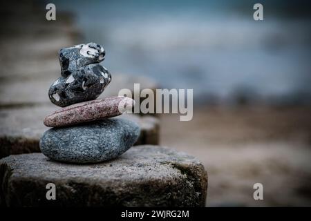 Ein Stapel ausbalancierter Steine vor einer ruhigen Wasserkulisse, die an Ruhe erinnert. Stockfoto