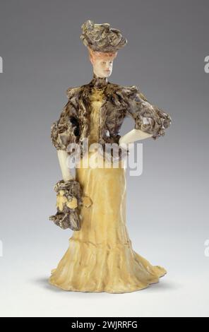 Edouard Lachenal und Henry Caro-Delvaille (1876-1928). "Junge Frau mit gelbem Kleid und schwarzem Astrakan Bolero". Steingut. Museum der Schönen Künste der Stadt Paris, Petit Palais. 25794-11 Zubehör, schwarzer Astrakan, Bolero, Fayence, junge Frau, dekoratives Objekt, gelbes Kleid, Statuette, Hut Stockfoto