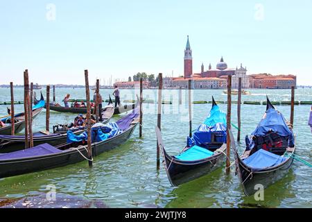 Kirche San Giorgio Maggiore und St. George Bell Tower in der Ferne mit Gondeln im Vordergrund in Venedig, Italien. Stockfoto