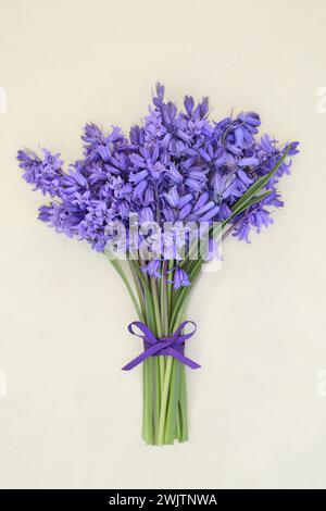 Blumenkraut für Frühling auf Hanfpapier Hintergrund gebunden mit lila Schleife und losen Blumen. Blumengeschenk Geschenkkarte zum Geburtstag, Stockfoto
