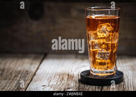 Eistee mit viel Eis in transparentem Glas auf rustikalem Holztisch Stockfoto