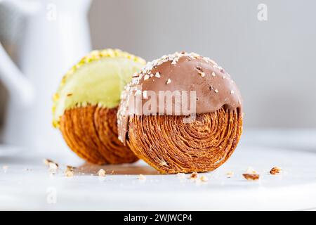 Fusion Croissant süßes Gebäck Cromboloni. New York Dessert. Runder Blätterteig mit Sahne gefüllt und mit weißer Milchschokolade oder Pistazien glasiert Stockfoto