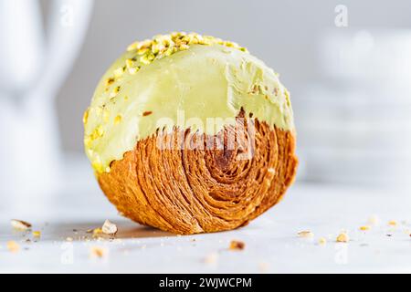 Fusion Croissant süßes Gebäck Cromboloni. New York Dessert. Runder Blätterteig mit Sahne gefüllt und mit weißer Milchschokolade oder Pistazien glasiert Stockfoto