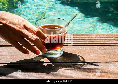 Frau trinkt Kaffee im Schwimmbad. Morgenkaffee am Pool. Stockfoto