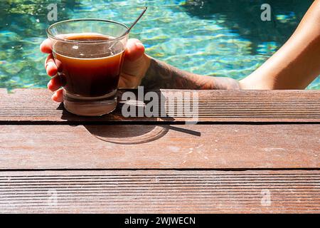 Frau trinkt Kaffee im Schwimmbad. Morgenkaffee am Pool. Stockfoto