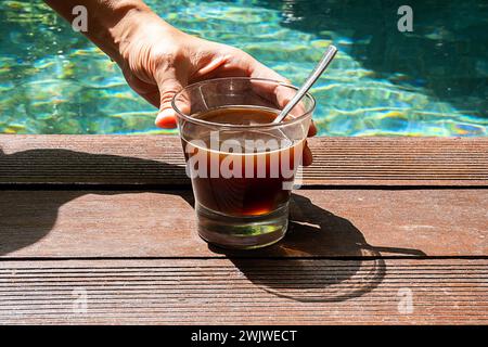 Frau trinkt Kaffee im Schwimmbad. Morgenkaffee am Pool. Stockfoto