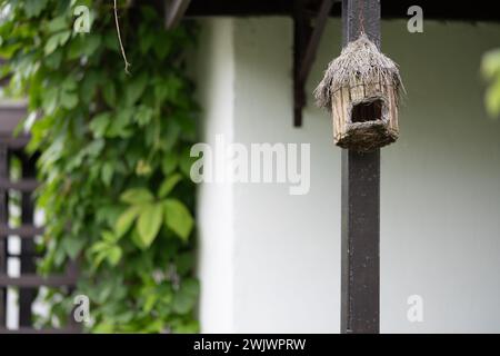 Ein Vogelhaus aus Zweigen, die im Garten hängen. Stockfoto