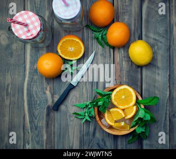 Zubereitung von erfrischenden Fruchtsäften im Sommer. Zitrusfrüchte und aromatische Kräuter auf einem Holztisch. Das Konzept einer gesunden Ernährung und Entgiftung. Vitamine Stockfoto