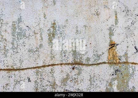 Abblätternde und rissige Farbe auf einem alten Blech mit einer krummen, rostigen Linie. Stockfoto