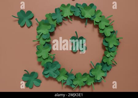 St. Patrick's Day Hintergrund mit Schamrock auf pfirsichfarbenem Hintergrund. Klee hinterlässt einen Kranz, Papierbasteln. Stockfoto