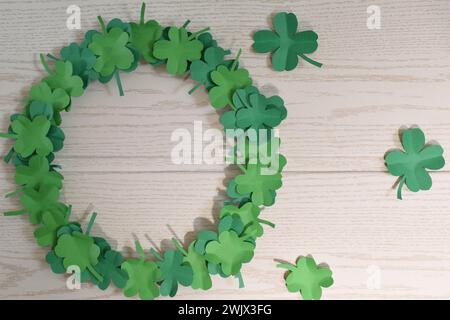 St. Patrick's Day Hintergrund mit Schamrock auf hölzernem Hintergrund. Klee hinterlässt einen Kranz, Papierbasteln. Stockfoto