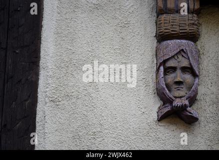 Handgeschnitzte Holzfigur an der Fassade eines Fachwerkhauses in Turckheim, Elsass Frankreich. Stockfoto